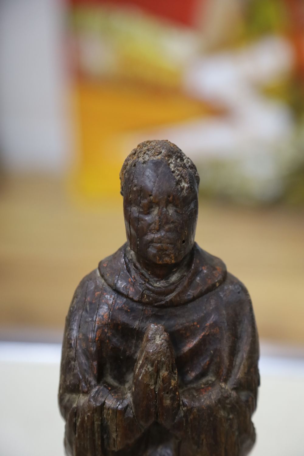 A carving of a saint in prayer, on stand